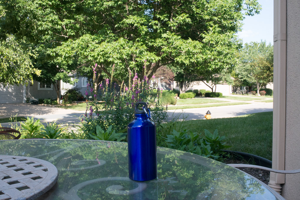 Picture of a blue water bottle on a glass table shot with a deep depth of field with wide angle