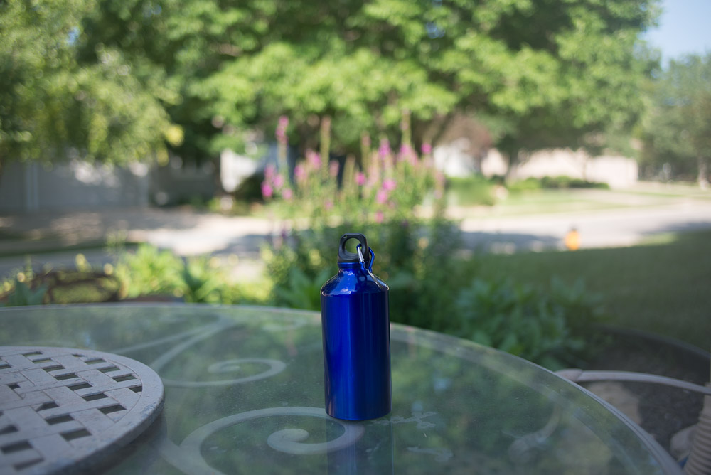 Picture of a blue metal water bottle outside shot at a wide open aperture