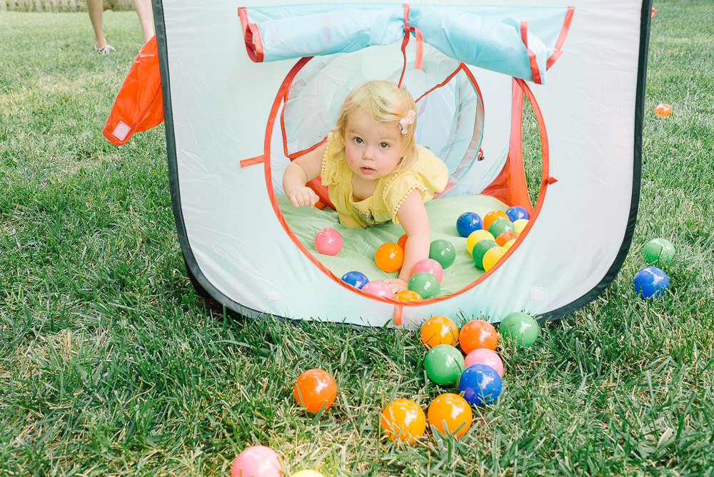 image of blonde girl climbing through ball tunnel at a one year old's birthday party