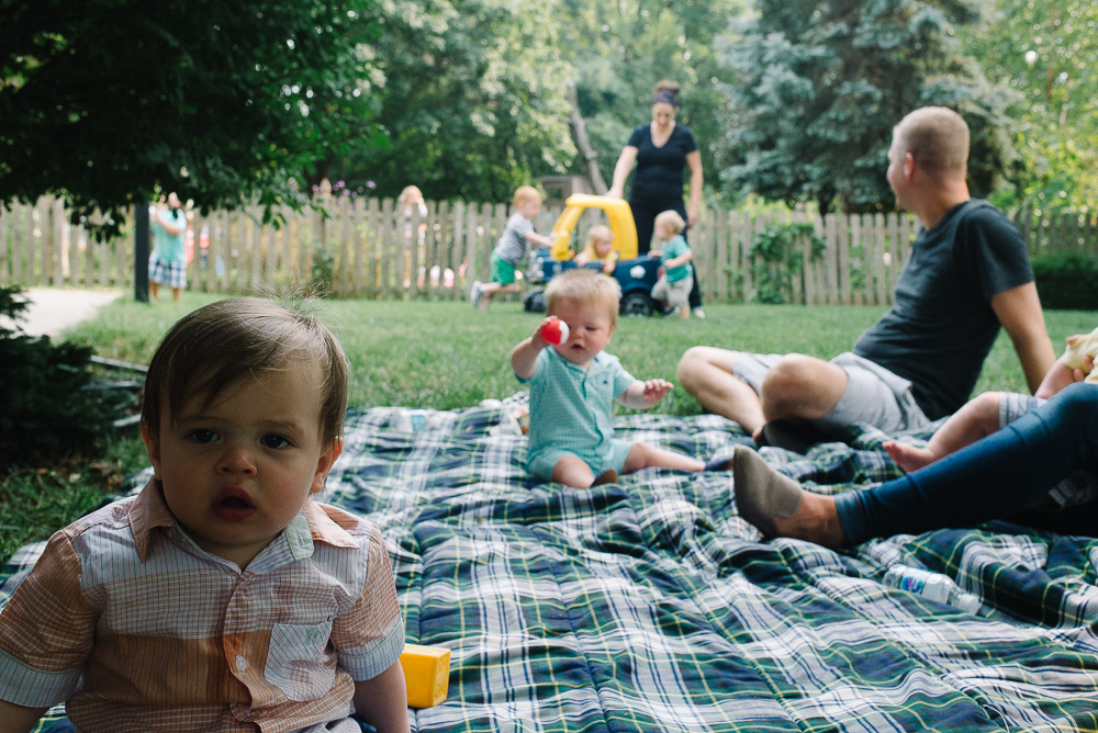 image of a one year old at his first birthday party with guests and kids in the background