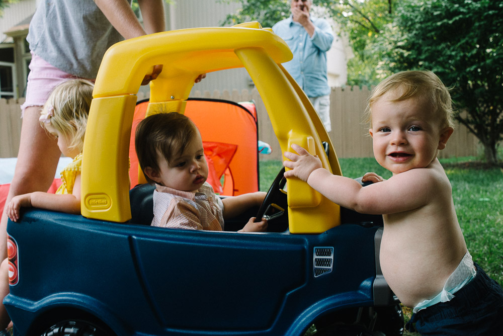 image of kids smiling and playing in a car toy that one got for his one year old birthday party