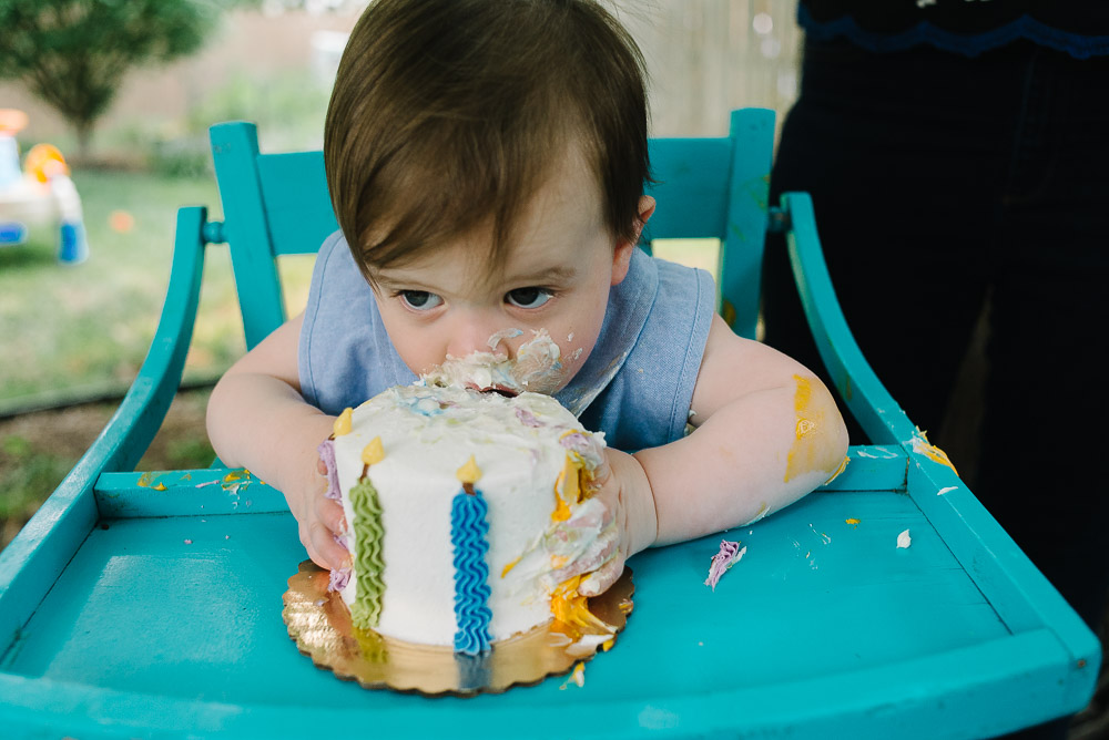 image of a one year old at his first birthday party eating cake for the first time