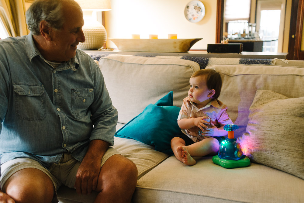 image of a one year old on his first birthday party playing with a new toy and looking at his grandpa