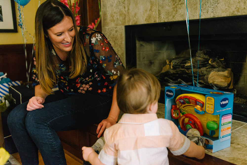 image of a one year old opening up a present with his mom at the end of his first birthday party