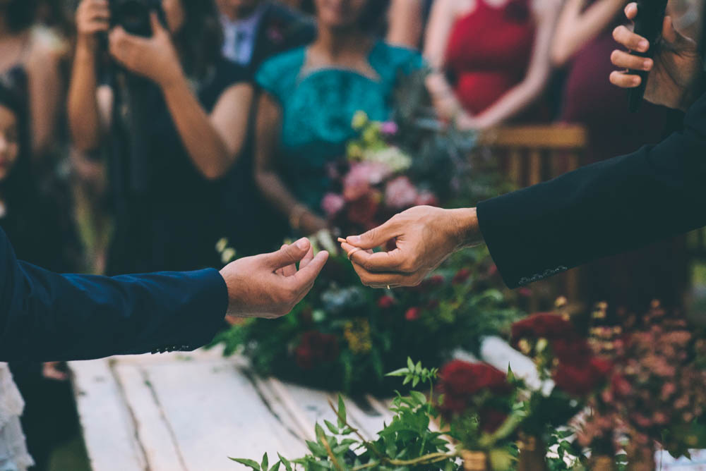 image of a priest handing a groom a wedding ring, a good reason to shoot with two cameras for wedding photography