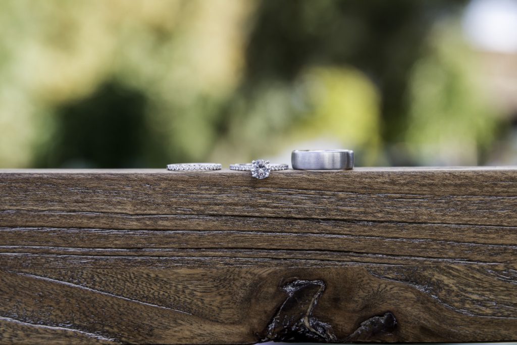 Image of wedding rings on brown wood with a background of nature out of focus
