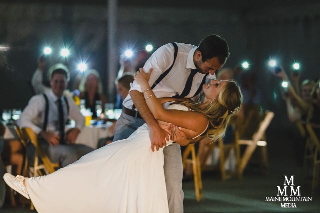 A bride and groom dancing as guests take pictures.