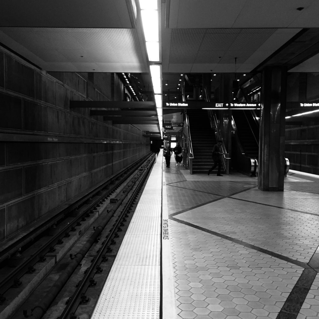 A dark black and white photo in a subway with a leading line down the middle of the frame