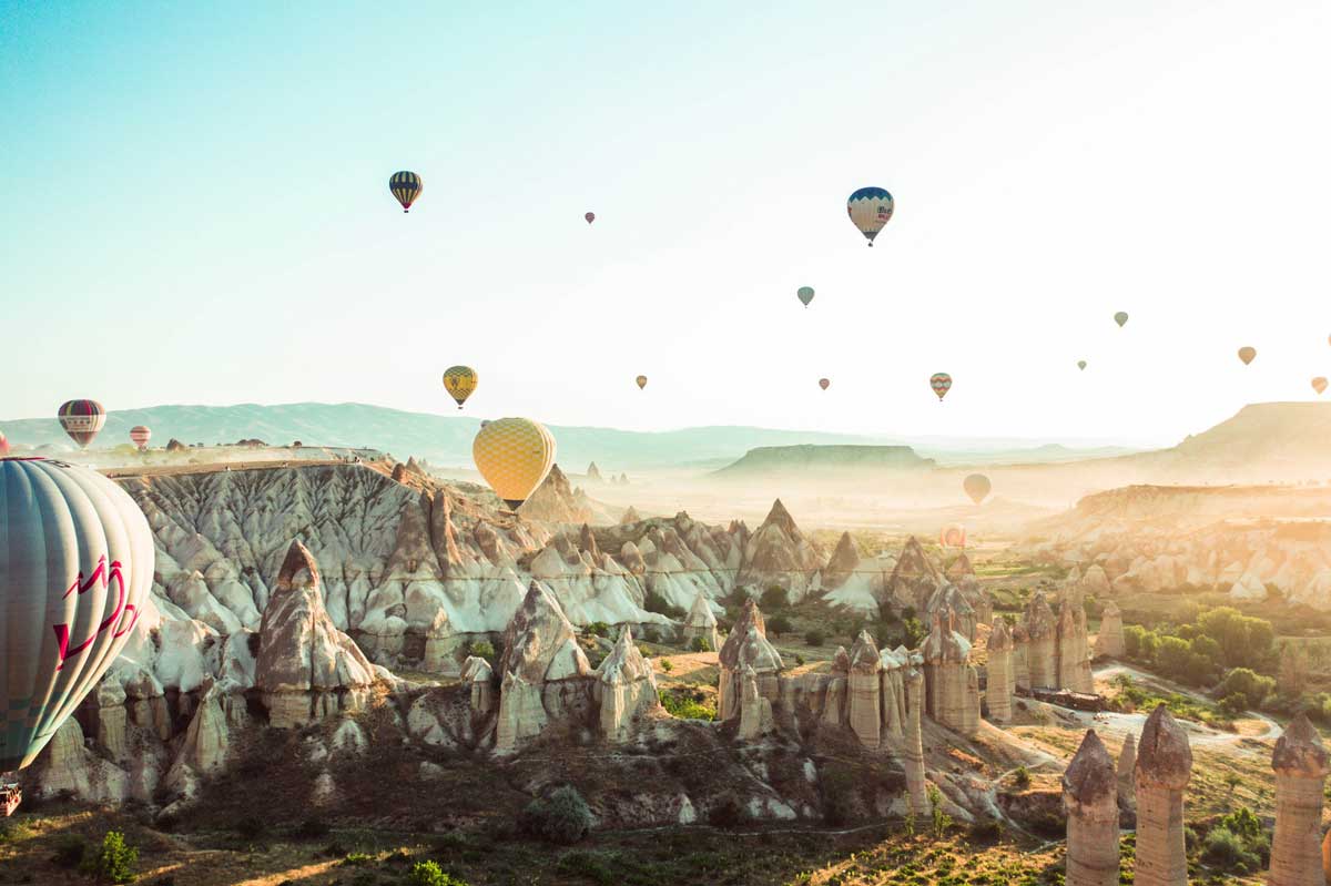 Travel photography image of hot air balloons in a canyon and mountains