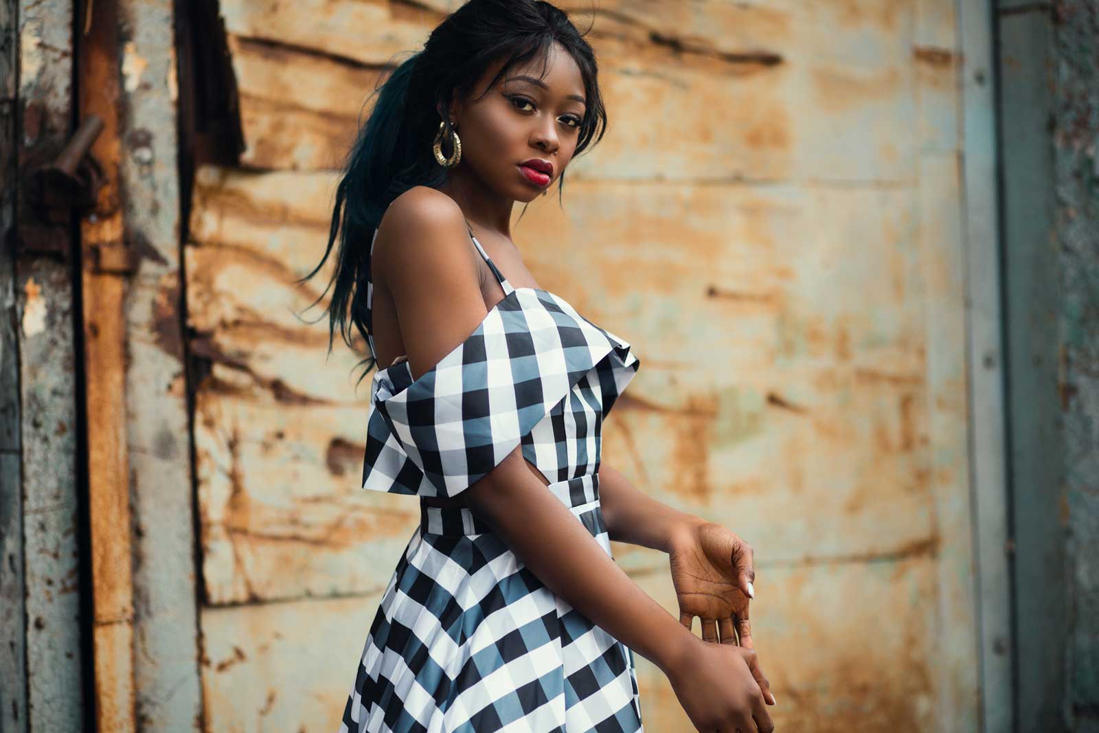 A woman in a black and white checkered dress in front of a stone wall