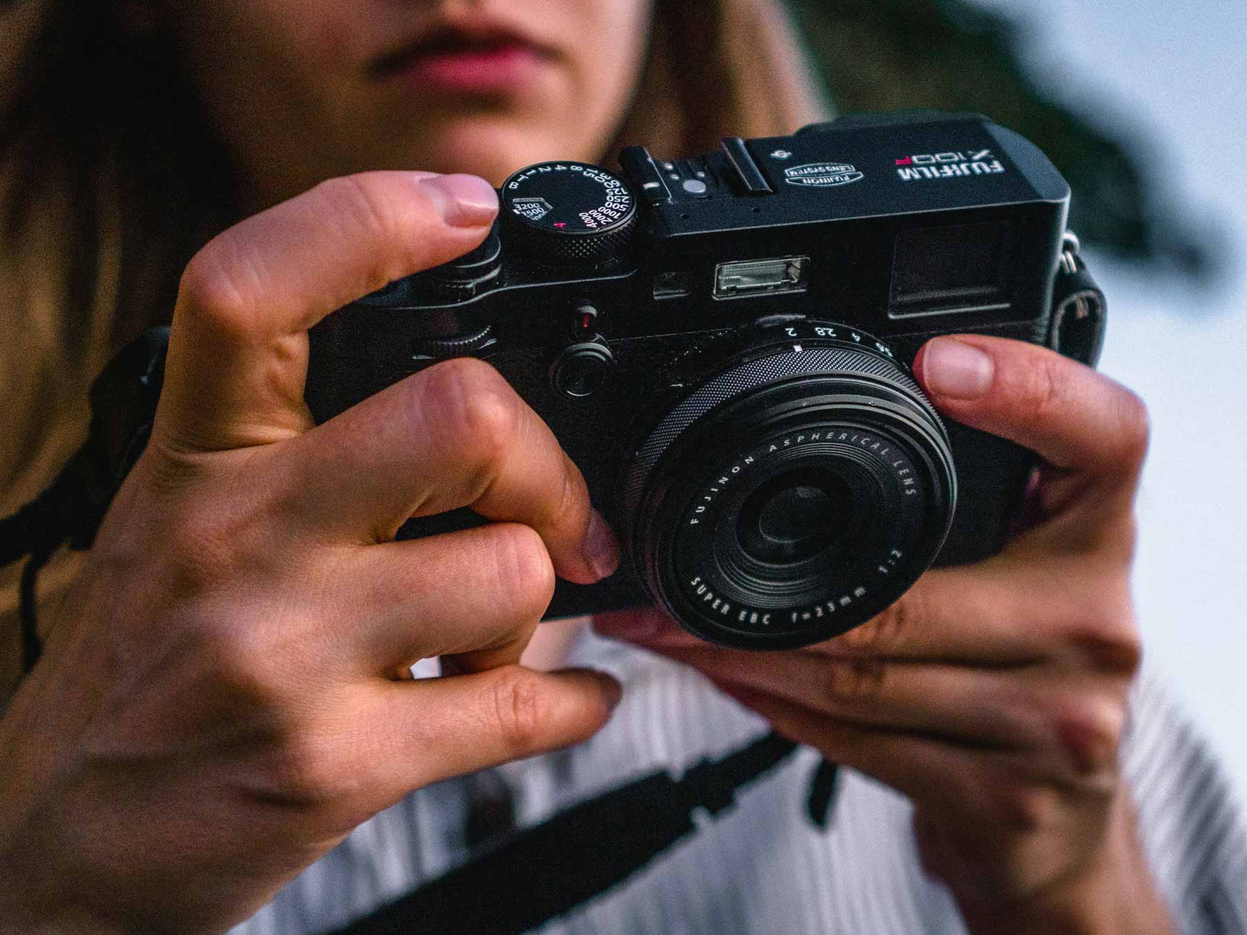 A woman holding a small Fujifilm camera.