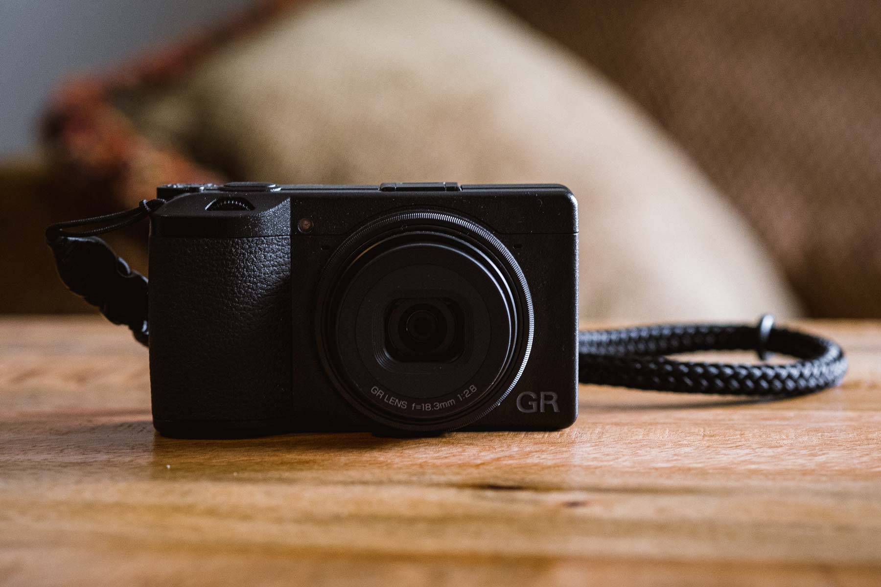 A Ricoh GRIII on a wood table in natural light.