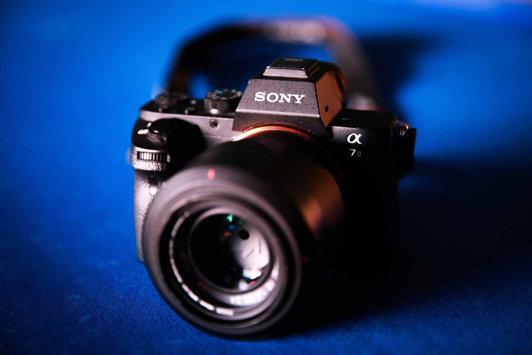 A Sony A7II mirrorless camera on a blue surface.