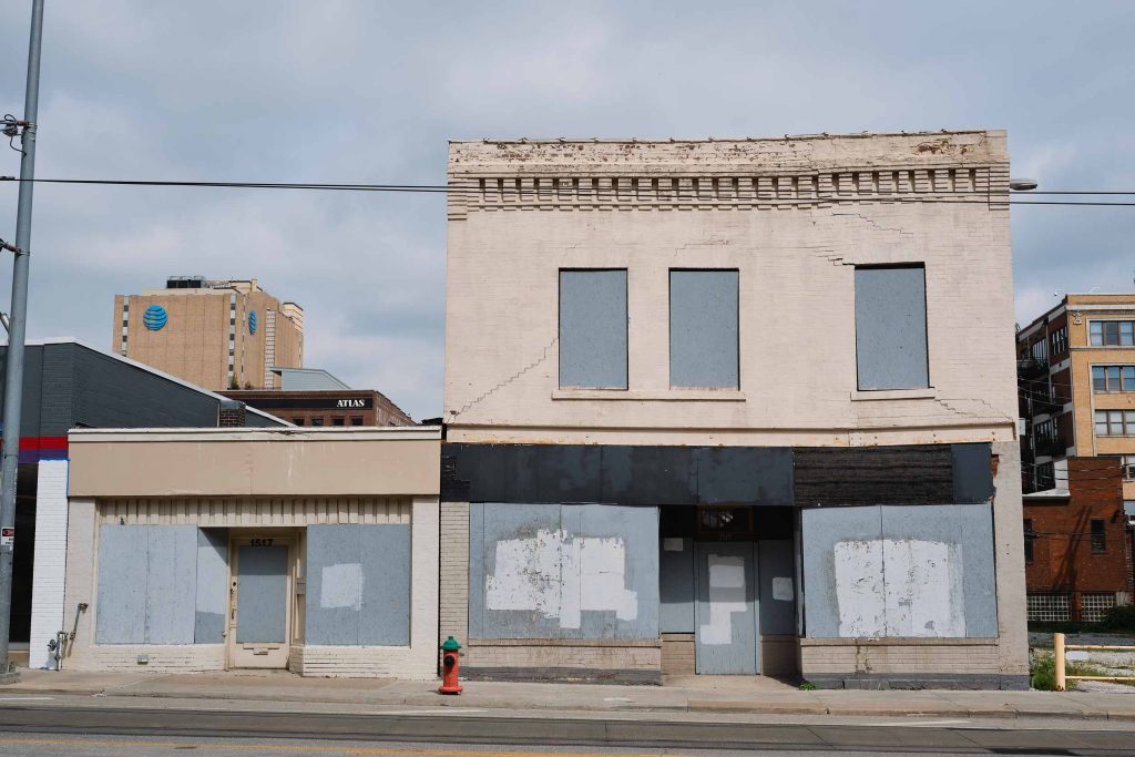 An old run-down light brick building from the front.