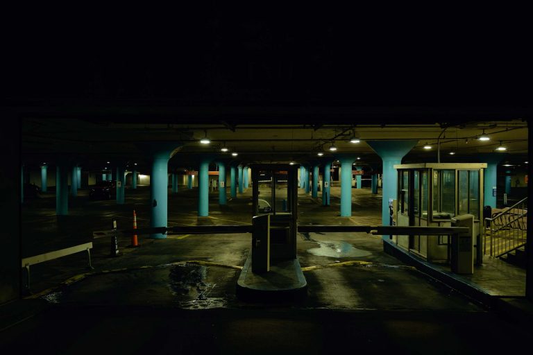 A parking garage at night with light blue columns.