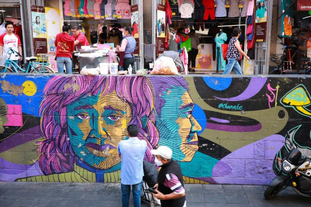 People in front of a street mural and shops