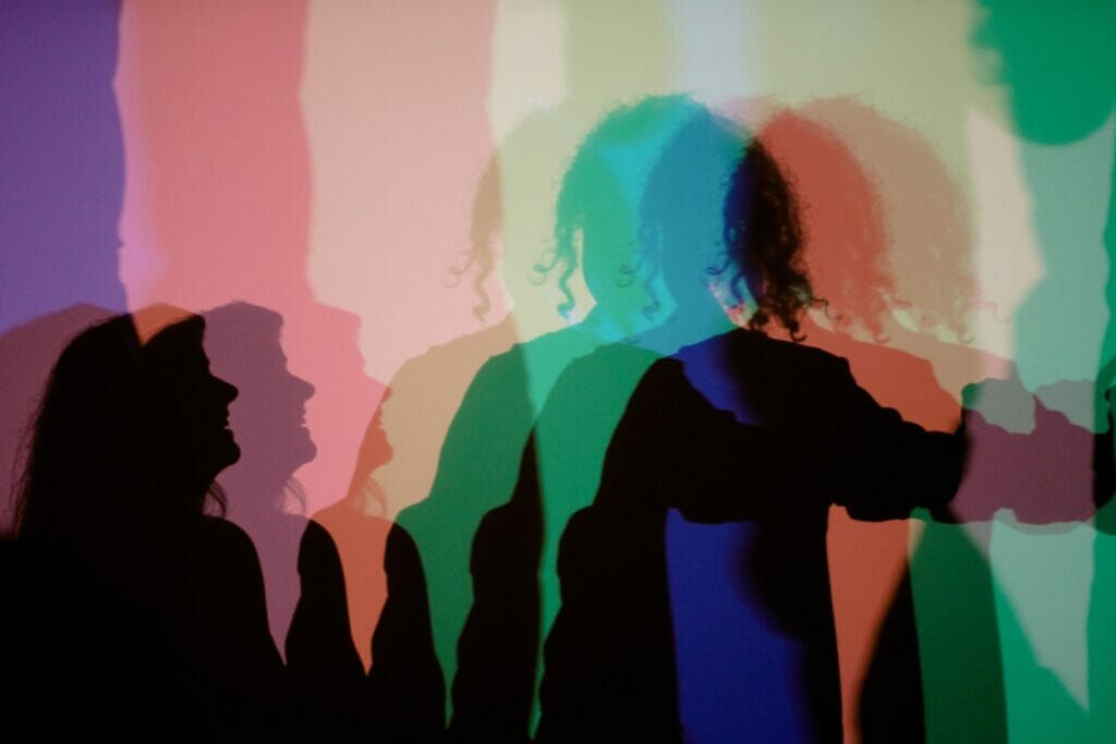 Silhouettes on a colored background - a woman smiling at someone with curly hair.