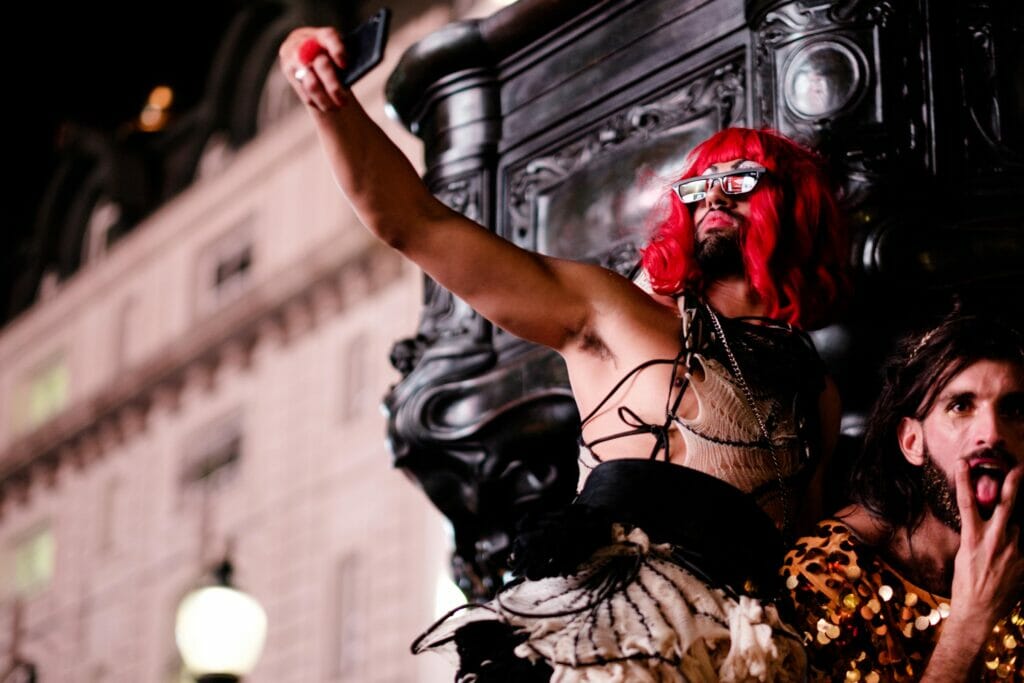 A man in a red wig taking a selfie with a phone. 