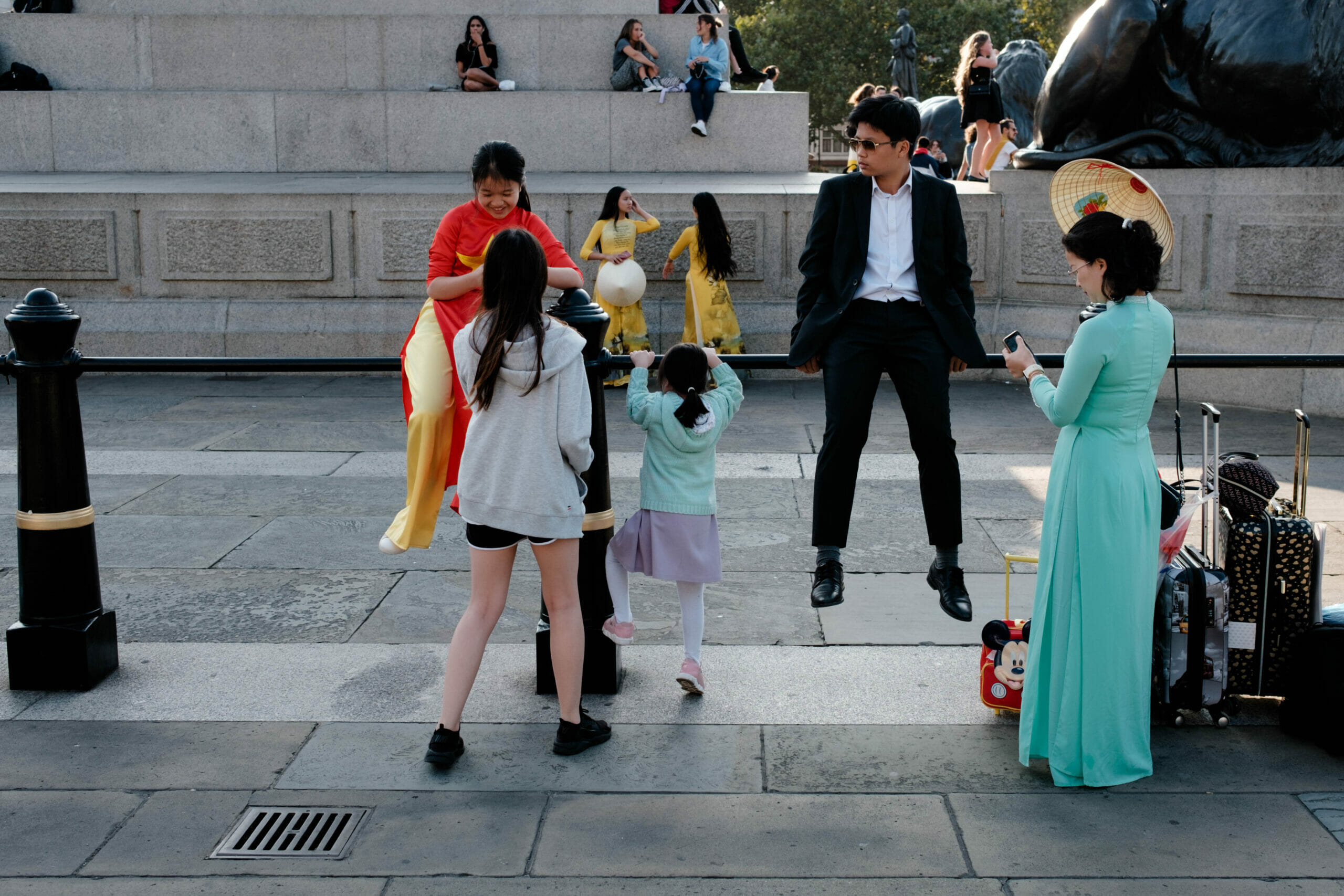 A family with luggage sitting on a handrail.