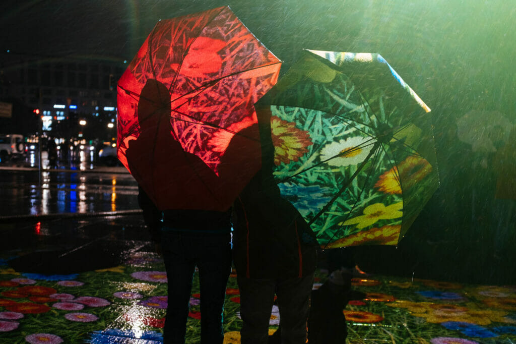 Two people from behind holding red and green umbrellas.