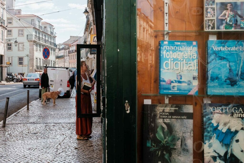 Woman in a dress entering a bookstore. A man walking a dog with a cone on.