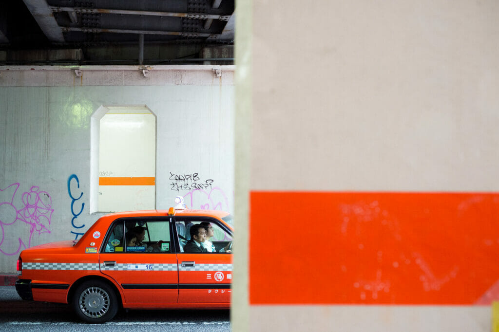An orange taxi going in the direction of an orange line on the wall in front of it.