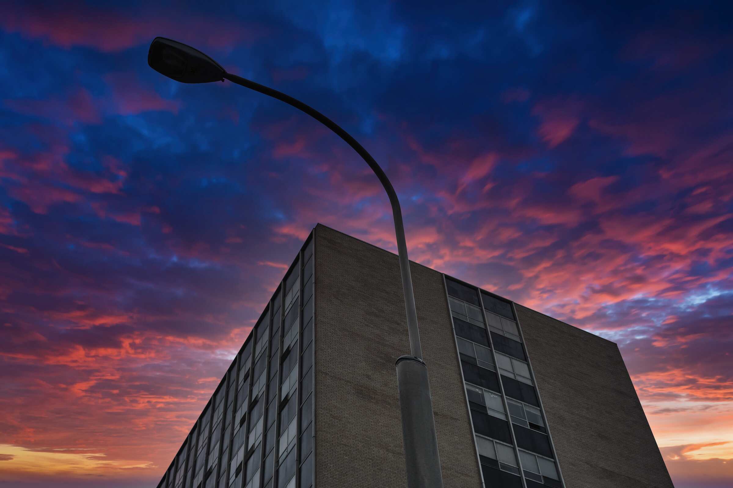 Looking up at a lamppost and a building and a dramatic sky edited in.