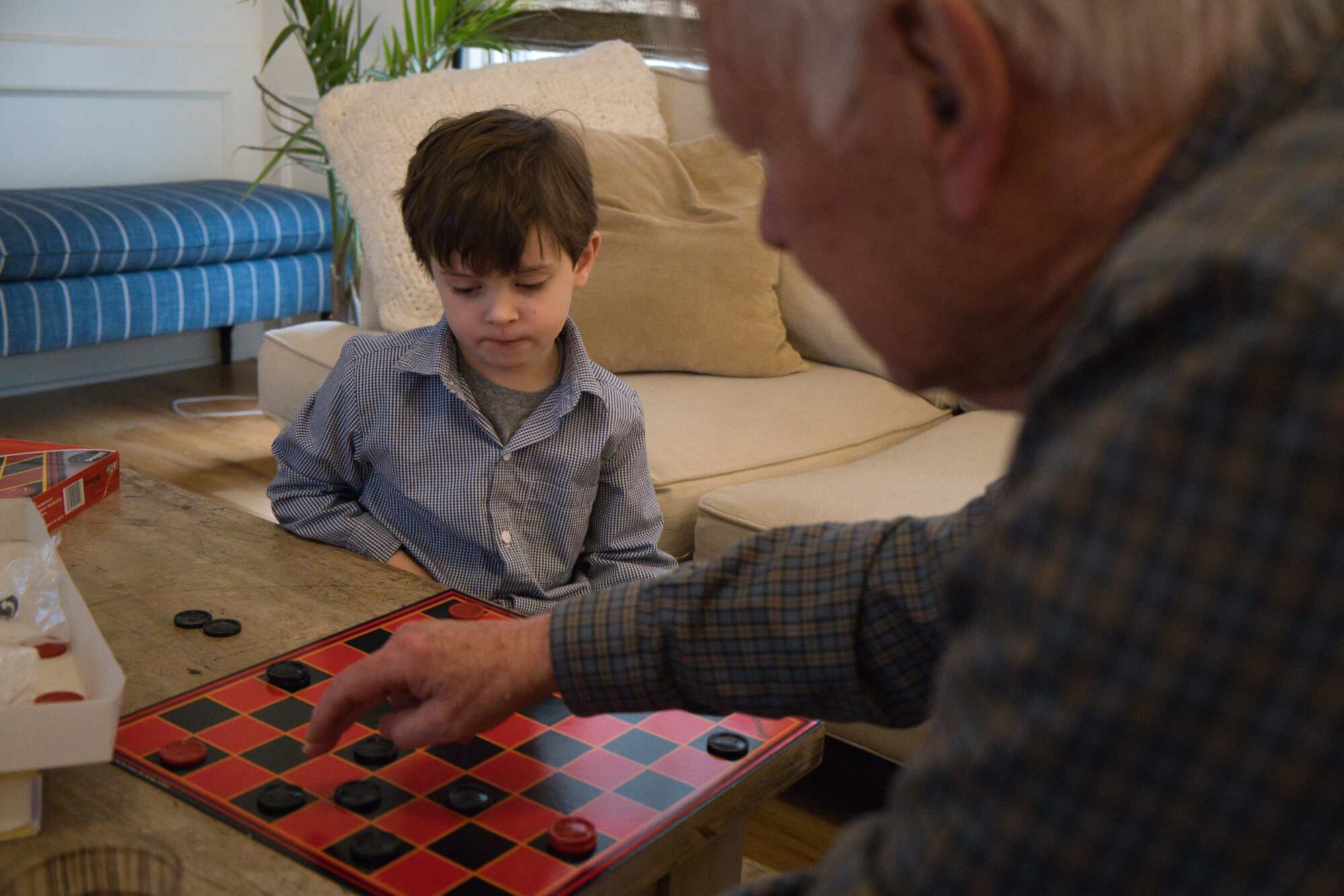 Man and boy playing checkers with noise reduction.