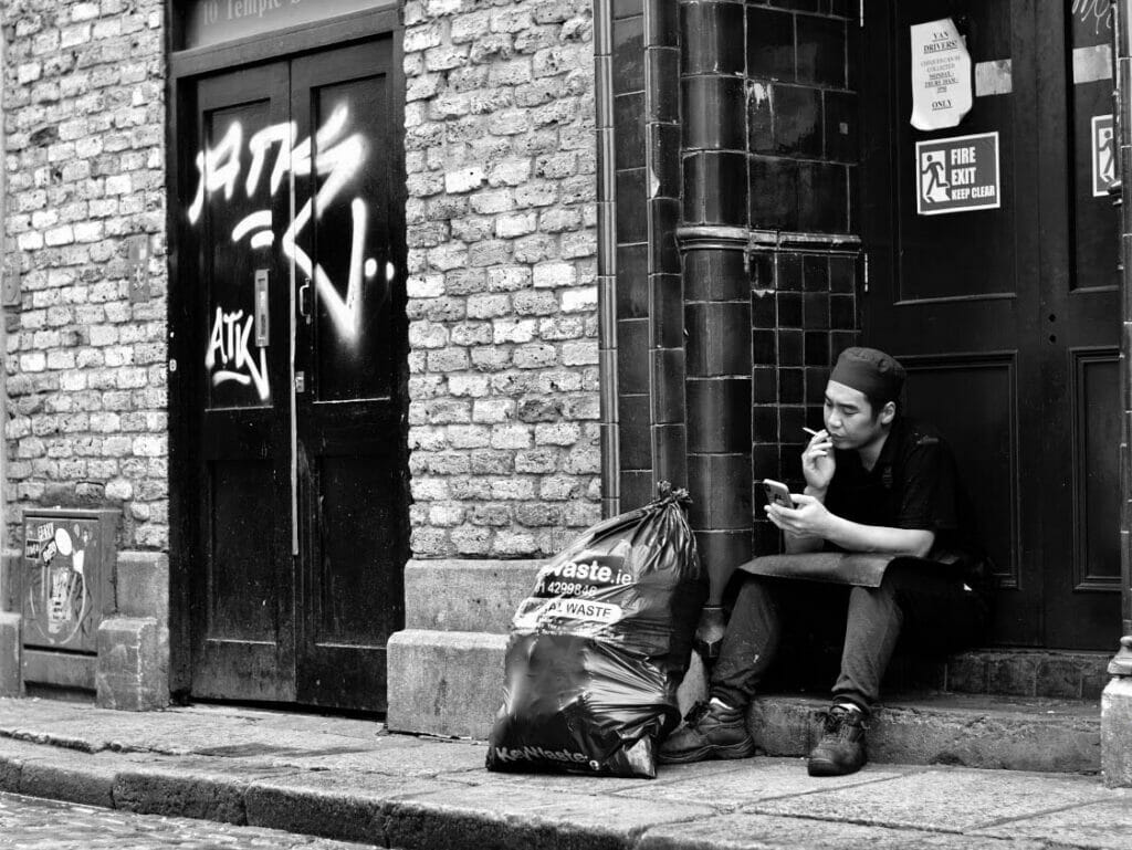 A man sitting in a doorway smoking a cigarette.