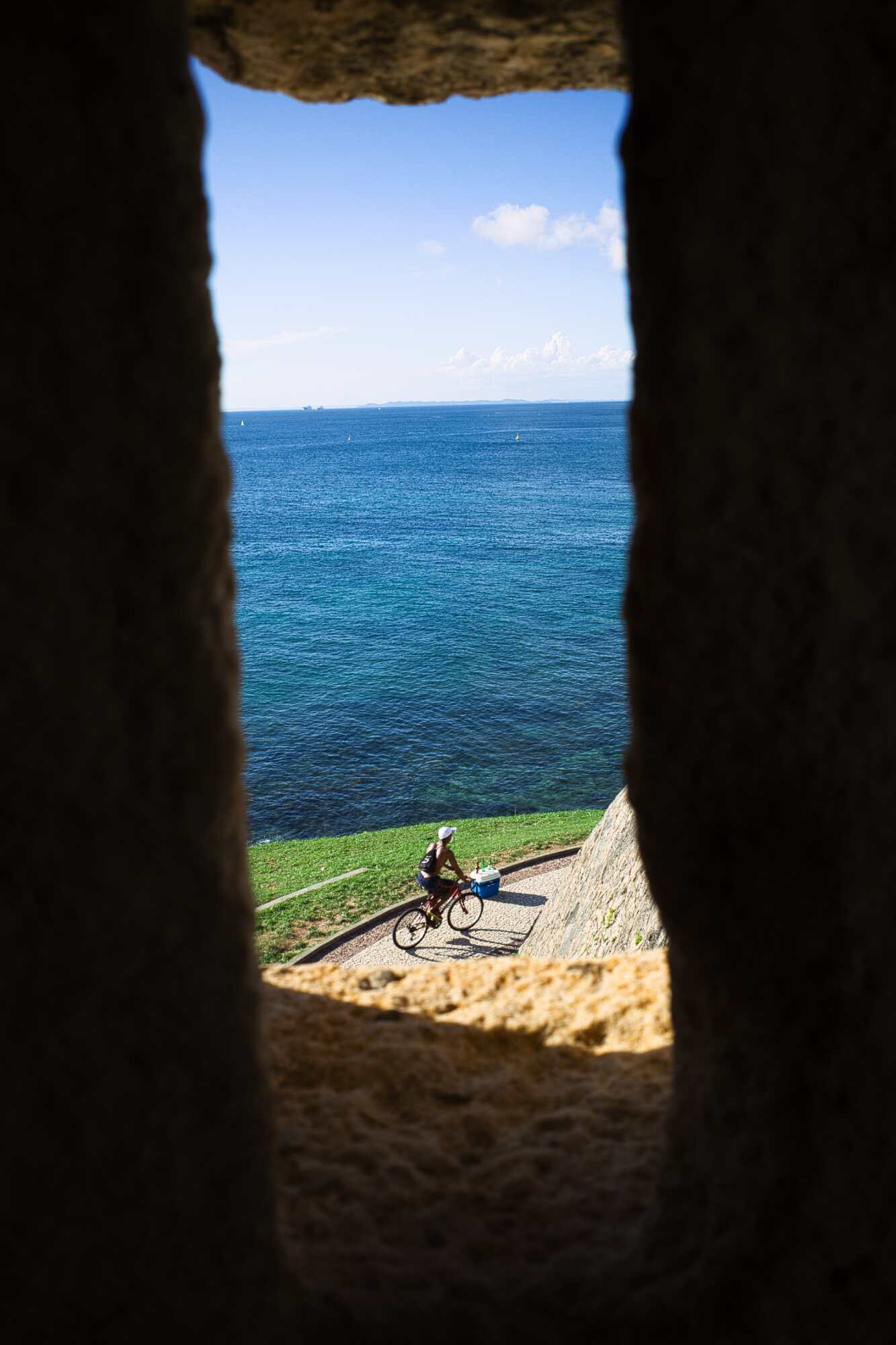 Looking out a window of a lighthouse to a man on a bike after editing.