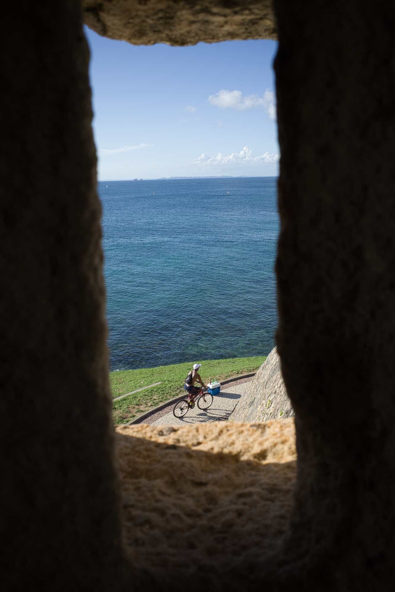 Looking out a window of a lighthouse to a man on a bike before editing.