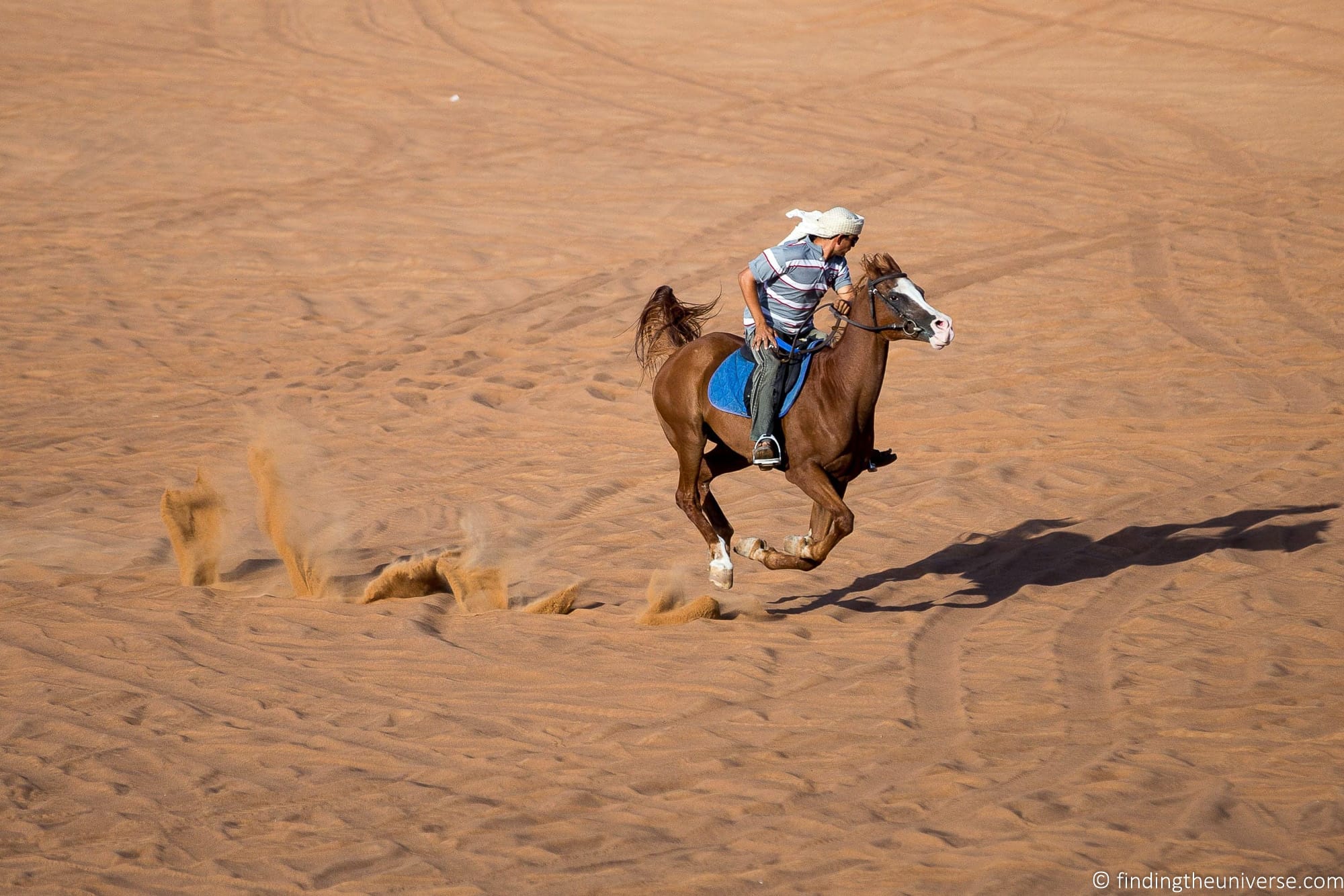A man riding a horse in a desert in Dubai.