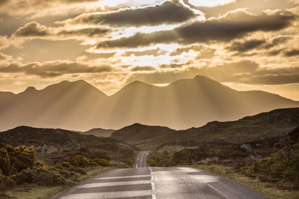 A road leading to mountains at sunrise.