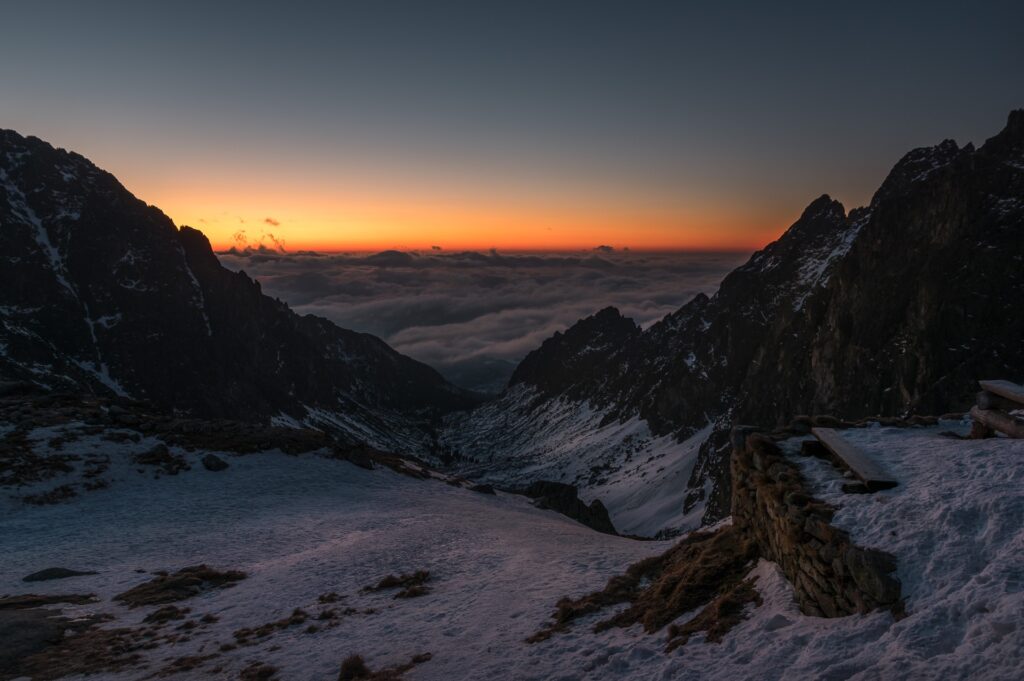 Teryho Chata at sunrise with clouds below mountains.