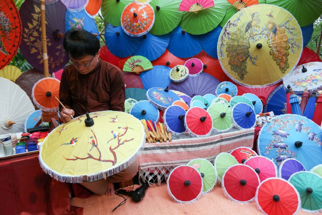 An artisan painting designs on an umbrella.