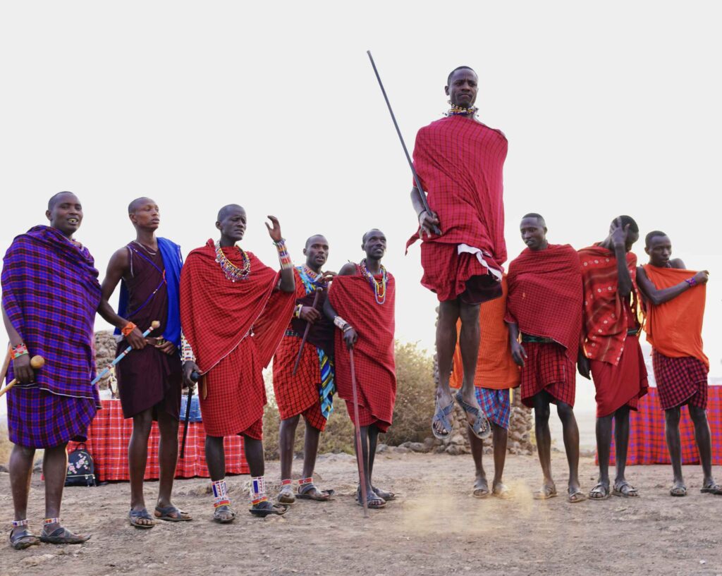Men of an African tribe with a man in front jumping high.