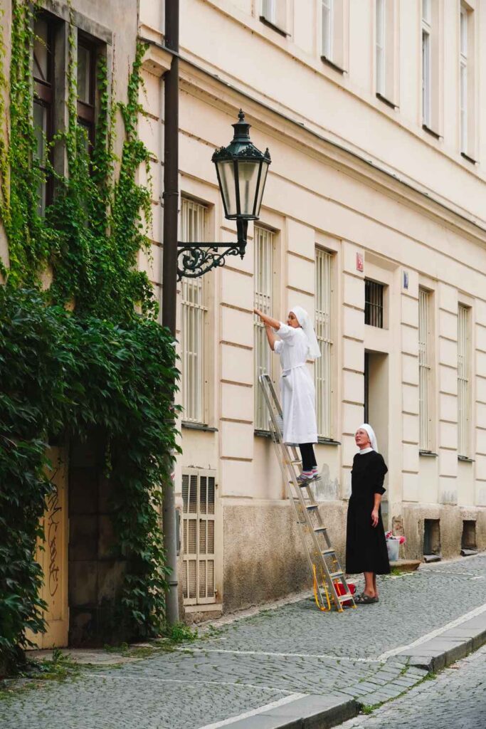 Two nuns doing work on the side of a building.
