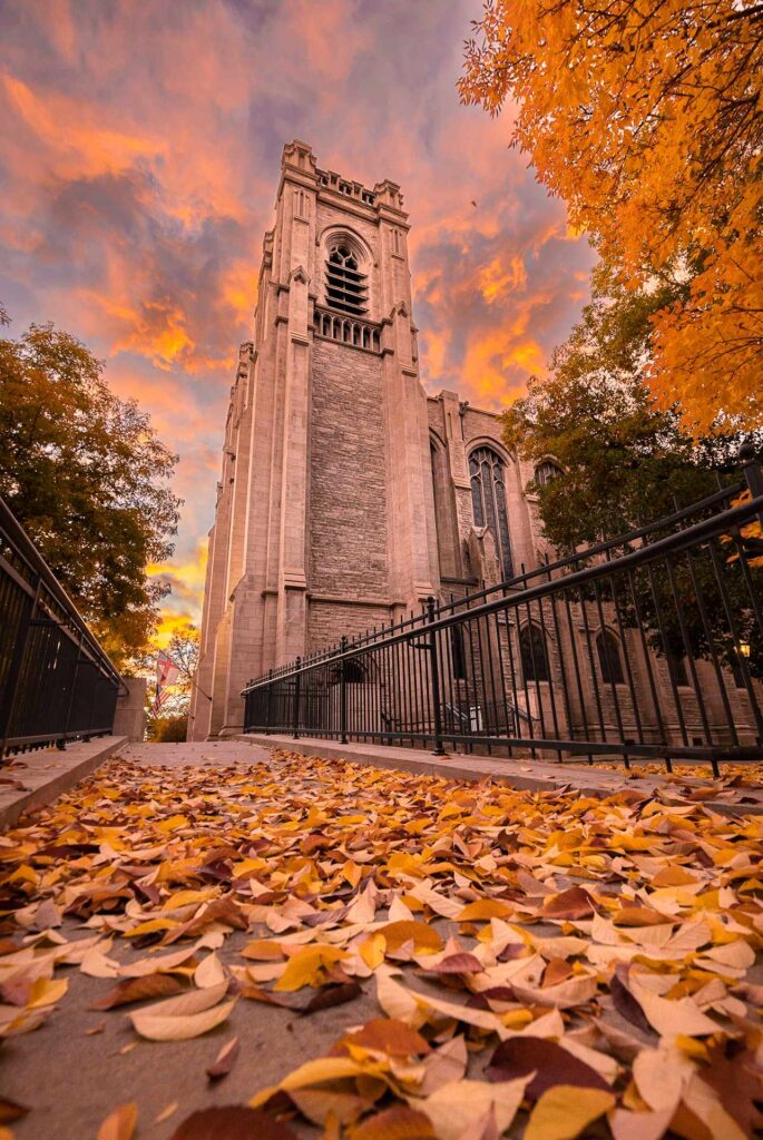 A church from a low angle at golden hour and a sidewalk with fallen leaves.