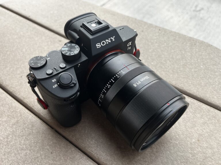 The 7Artisans AF 35mm F1.8 Full Frame Lens on a Sony a7 III camera body on a brown outdoor table.