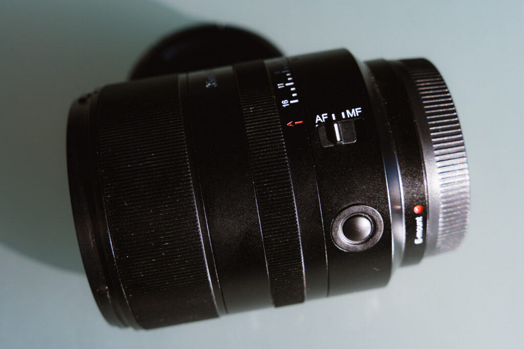 The side of the 7Artisans AF 35mm f/1.8 Full Frame Lens showing its AF/MF switch and custom button.